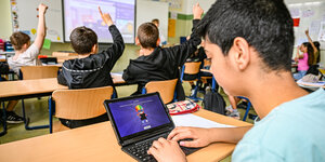 Kinder sitzen mit Laptops in einem Klassenzimmer