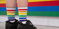 Eine Person trägt Socken in den Regenbogenfarben