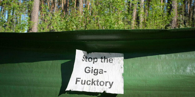 Ein Zettel mit dem Schriftzug ·Stop the Giga-Fucktory· klebt nahe dem östlichen Teil des Werksgeländes der Tesla Gigafactory und des Protest-Camps im Wald an einem Krötenschutzzaun