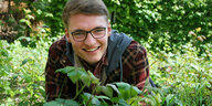 Selbsternannter Plantfluencer und Natur Reporter Robinga Schnögelrögel liegt auf einer Wiese und lächelt in die Kamera.