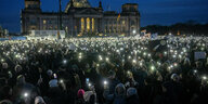 Demonstrierende im Dunkeln, die Handytaschenlampen und Schilder hochhalten