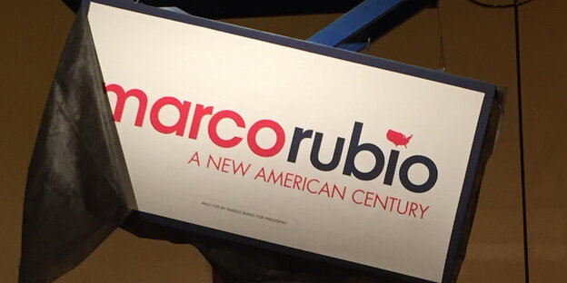 Ein Schild „Marco Rubio. A new American Century" hängt schief an einem Gestell. Ein Schild „Marco Rubio. A new American Century" hängt schief an einem Gestell.