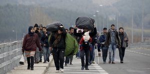 Eine Gruppe von Flüchtlingen marschiert auf eine der Sraße in Richtung griechisch-mazedonischer Grenze
