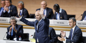 Gianni Infantino steht mit ausgebreiteten Armen vor seinen sitzenden Kollegen auf einem Fifa-Kongress.