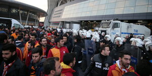 Fußballfans vor einem Stadio, das von Polizisten abgesperrt wird