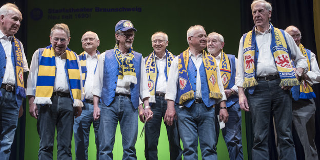 Die Senioren vom "Club der 67er" stehen mit blau-gelben Fanschals auf der Bühne.