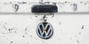 VW-Symbol auf dem Heck eines Autos. Der Lack ist zerkratzt