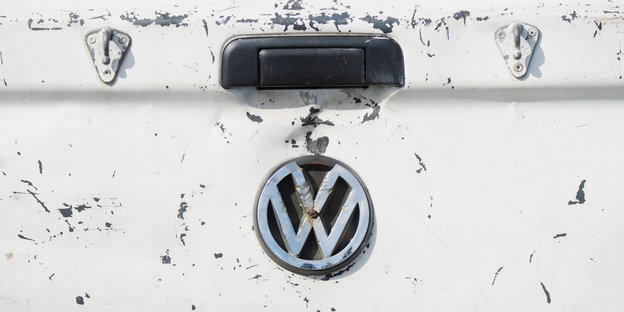 VW-Symbol auf dem Heck eines Autos. Der Lack ist zerkratzt