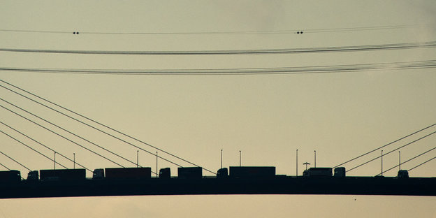 LKWs fahren im Sonnenuntergang auf der Köhlbrandbrücke in Hamburg