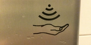 Ein Seifenspender mit einem WLAN-artigen Piktogramm und einer Hand darunter