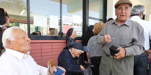 Männer und Frauen gehobeneren Alters vor einem Wahlbüro
