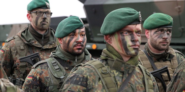 Soldaten stehen mit Tarnfarben im Gesicht