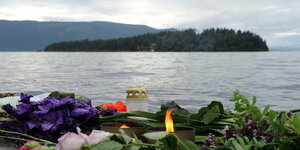 Blumen und Kerzen, dahinter Wasserfläche mit einer Insel
