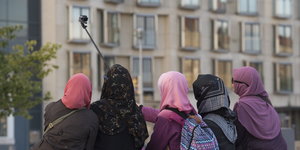 Fünf Frauen mit Kopftuch fotografieren sich mit einem Selfiestick