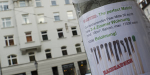 Ein Zettel mit einem Wohnungsgesuch hängt an einem Laternenmast in München.