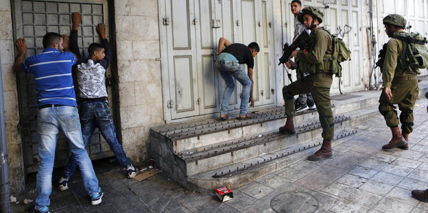 Israelische Soldaten halten palästinensische Jugendliche mit vorgehaltenem Gewehr in Schach