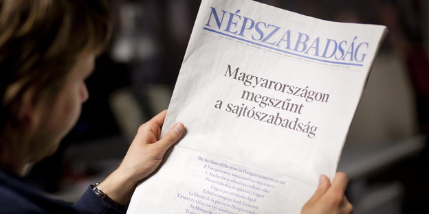 Eine Frau hält eine Ausgabe der Népszabadság in ihrer Hand