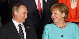 Putin und Merkel schauen sich lächelnd an