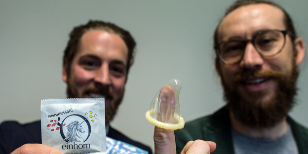 zwei Männer, einer hat ein Kondom über den Finger gestülpt zwei Männer, einer hat ein Kondom über den Finger gestülpt