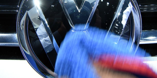Das VW-Logo auf dem Kühlergrill wird geputzt