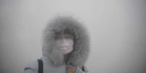 Eine Fraum mit Atemmaske im Smog