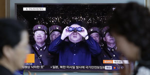 Auf einem Fernseher ist Kim Jong Un zu sehen. Er guckt durch ein Fernglas