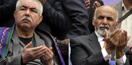 Raschid Dostum und Aschraf Ghani sitzen nebeneinander und haben die Hände zum Gebet erhoben
