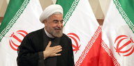 Der iranische Präsident Hassan Ruhani tritt vor die Presse; im Hintergrund sieht man iranische Flaggen