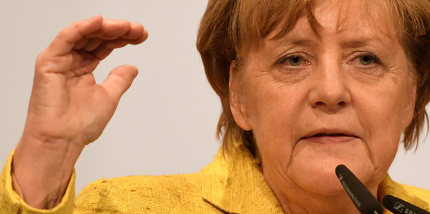 Angela Merkel hält die rechts Hand hoch