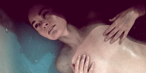 Eine Frau liegt in der Badewanne und berührt ihre Brüste