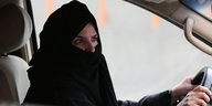Eine Frau mit schwarzem Gesichtsschleier sitzt am Steuer eines Autos