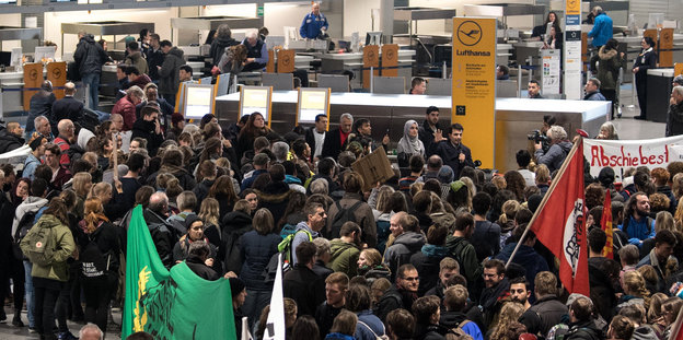 Eine Menschenmenge steht vor einem Flughafen