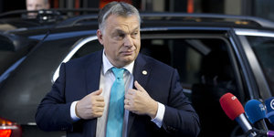 Orban steigt aus einem Auto und rückt sich die Jacke zurecht