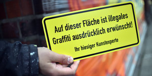 Hand mit Schild, das Graffit-Sprayen ausdrücklich erlaubt Hand mit Schild, das Graffit-Sprayen ausdrücklich erlaubt