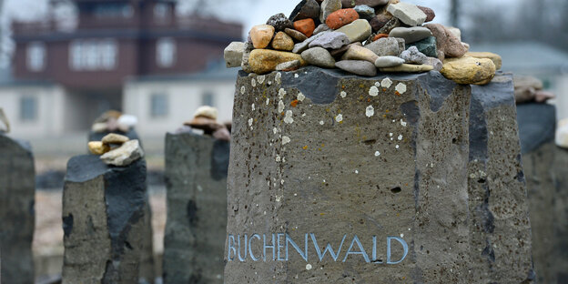 Kleine Steine liegen auf einem Gedenkstein mit der Aufschrift „Buchenwald“