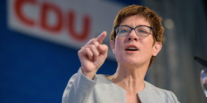 eine Frau zeigt mit dem rechten Zeigefinger nach vorne, im Hintergrund ein CDU-Logo