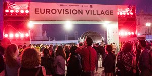 Menschen vor Schriftzug Eurovision Village