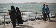 Zwei Frauen mit Kopftüchern und zwei Männern in Tshirts und Hosen stehen an einer Wasserfront und machen Fotos