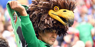 Ein mexikanischer Fan steht im Stadion mit einem Adler auf dem Kopf und schaut melancholisch drein