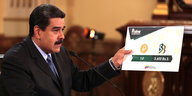 Venezuelas Präsdent Maduro hält ein Schild in der Hand, auf dem steht, dass ein Petro zukünftig 3 600 Bolivar kostet.