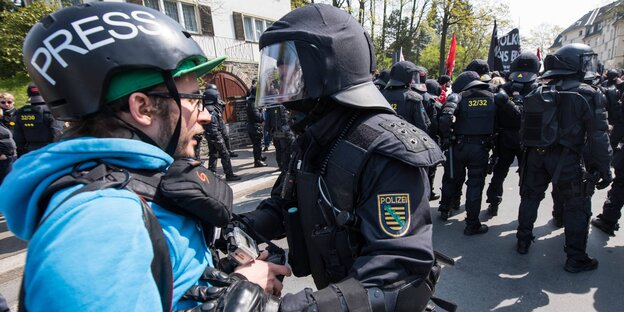 Ein Journalist und ein Polizist stehen nah beieinander