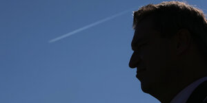 Das Profil eines Mannes, von Markus Söder, vor dem blauen Himmel, an dem ein Kondensstreifen zu sehen ist