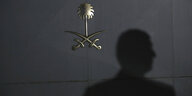 Schatten eines Menschen auf einer Tür mit saudischem Staatswappen