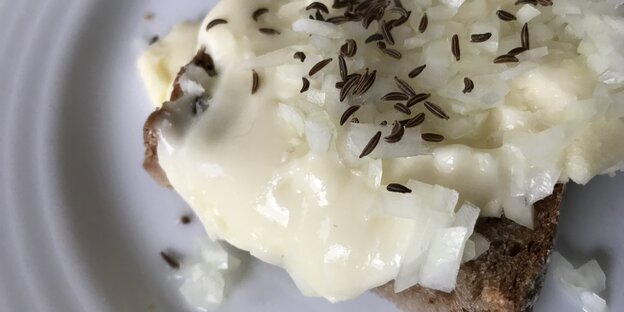 Eine hellgelbe Masse auf einem Brot, mit Kümmel bestreut Eine hellgelbe Masse auf einem Brot, mit Kümmel bestreut