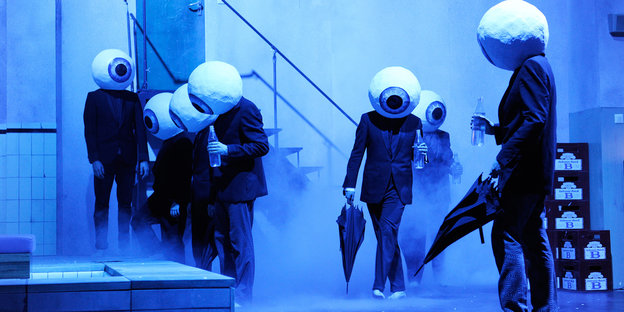 Alienartige Figuren auf einer blauvernebelten Bühne Alienartige Figuren auf einer blauvernebelten Bühne