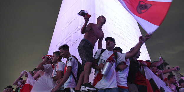 Männer jubeln, einer wedelt mit einer Fahne des Fußballclubs River Plate
