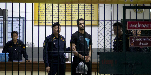 Fußballprofi al-Araibi umgeben von Gefängniswärtern hinter Gitterstäben