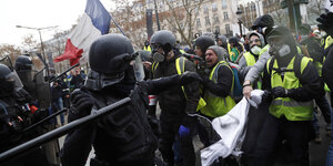 Ein Polizist setzt einen Schlagstock gegen Demonstranten der Gelbwesten ein