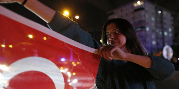 Eine Frau hält schräg von sich eine rote Fahne von sich, so wie ein Torero