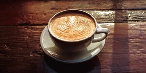 Eine Tasse voller Milchkaffee auf alten Holzdielen stehend